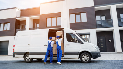 Two removal company workers unloading boxes from minibus into new home