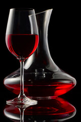 A glass of red wine and decanter on a glossy table.
