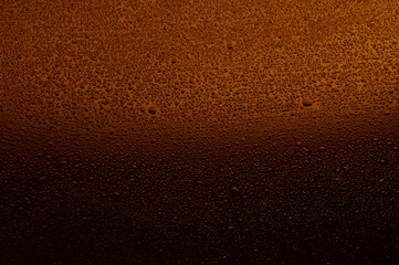 Fototapeta na wymiar Water drops on black glass. Background illuminated with orange ​light.
