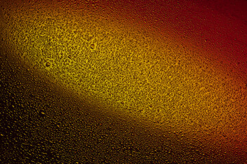 Water drops on black glass. Background illuminated with red and yellow ​light.