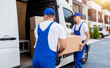 Two removal company workers unloading boxes from minibus into new home