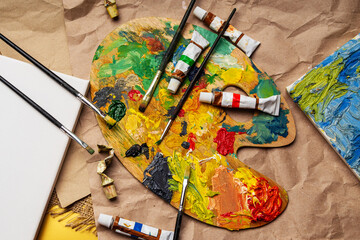 Wooden palette of the artist with used brushes and tubes of paint.