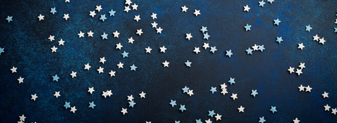 Fototapeta na wymiar White and blue small stars of sweets on a dark blue concrete or stone background. Selective focus. Christmas composition. Top view. Copy space