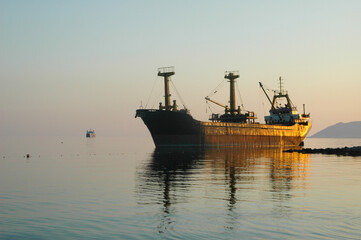 An old abandoned rusty ship near the shore. The ship ran aground.The ship is off the coast at sunset.
