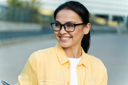 Portrait of the brunette purposeful woman wearing glasses looking away while spending time at the street before her work. Stock photo