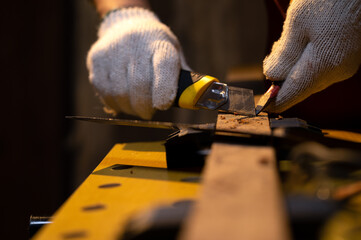 Close-up of Carpenter hands use old sharp Utility knife for manual sharpener pencil with fabric...