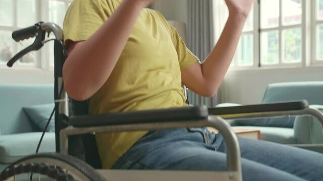 Close Up Of Asian Kid Girl Sitting In A Wheelchair While Wearing Virtual Reality Goggles At Home
