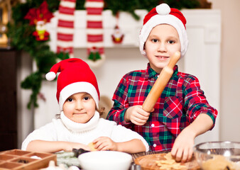 Kids in a Santa cap baking christmas cookies at home