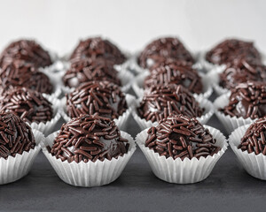 Brazilian sweet, traditional gourmet brigadeiro, fine pralines, in a slate plate. Selective focus