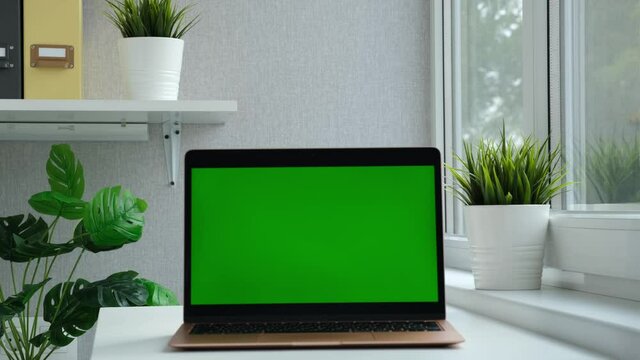 Morden laptop green screen. Chroma key green screen computer set up for work on desk at home or office, technology concept. Notebook empty for advertisement.