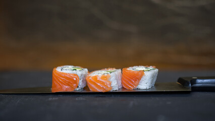Classic sushi with salmon. Pieces of rolls are laid out on a knife.