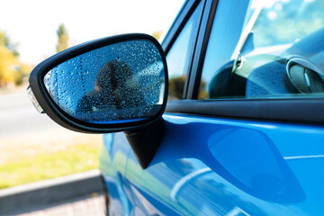 raindrops on the wet side-view mirror. rainy weather and car wash - obrazy, fototapety, plakaty