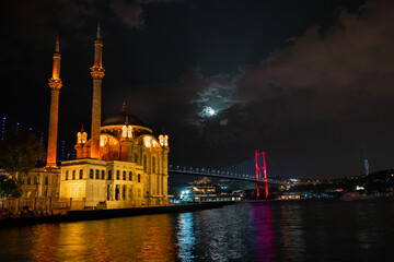 Ortaköy Mosque and Bosphorus Bridge during blue hour, full moon and blue night Sky. One of the most popular locations on the Bosphorus, Istanbul, Turkey.