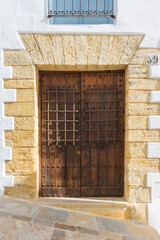 Wooden, aged door with iron grills and a lintel with keystones, rustic style