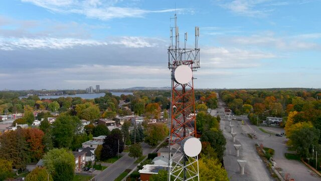 4K camera drone orbit around a cellular tower with autumn season colors in the background.