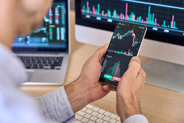Crypto trader investor broker using smartphone app analyzing financial data stock market price on...