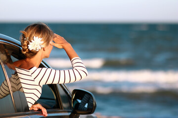 A Happy girl in the car by the sea in nature on vacation travel