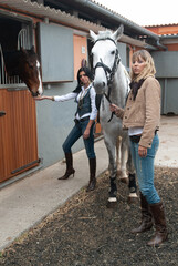 female jockeys in the arena preparing their horses to go out for a trot.  
