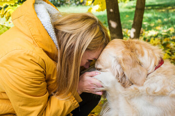 blonde woman hugs a retriever, holding his paws