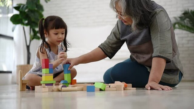 A 3 year old Asian girl is sitting, imagination and paying the wooden block toy, which is a toy that supports the development of children, to Asian girl and education concept.