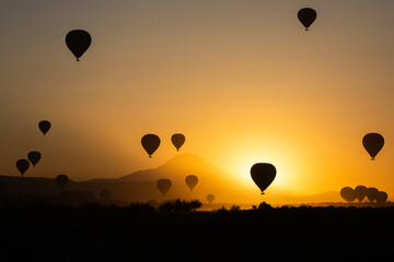 balloons taking off at sunrise orange with mountain in the background