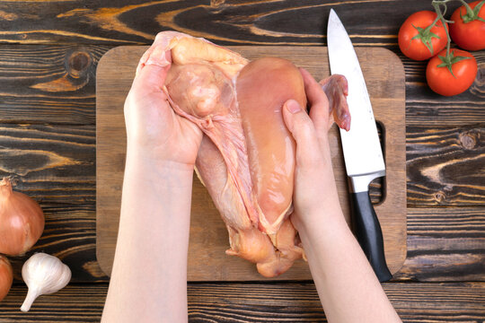 The chef's hands peel off the skin from the chicken breast. Chicken fillet