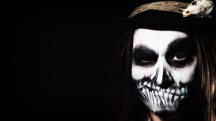 Young man wearing skull makeup in the dark. Halloween skeleton costume