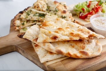 A view of a platter board featuring regular naan and garlic naan.