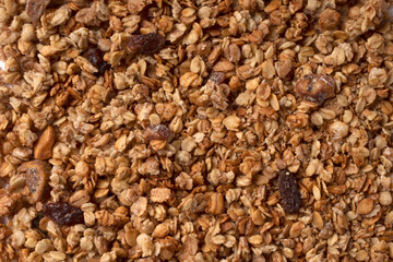 Organic granola with oats, raisins, nuts. Texture of muesli flakes as background. Top view. Blank space for text. Backplate for healthy nutrition concept. Vegetarian and vegan food for breakfast