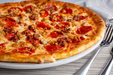 A view of a rustic sausage and pepperoni pizza.
