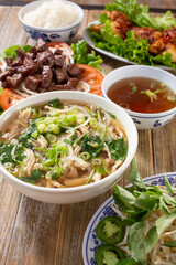 A view of an array of Vietnamese entree, featuring pho, shaking beef, and chicken wings.