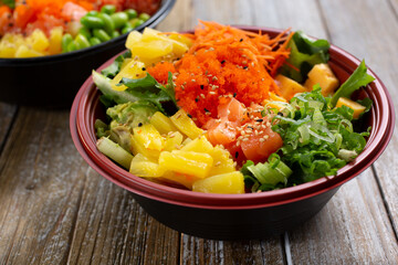 A closeup view of a customized poke bowl, featuring salmon and tobiko.