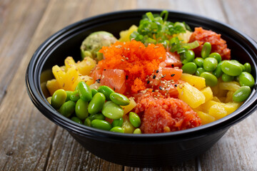 A view of a customized poke bowl featuring salmon, spicy tuna and edamame.