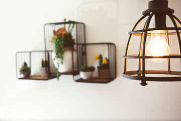 A view of a contemporary light fixture and a mounted wall decor design featuring metal shelves...