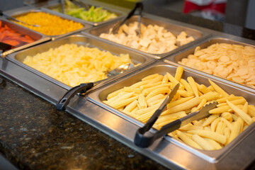 A view of a buffet table display featuring a variety of raw vegetables ready to be cooked, seen at a local Mongolian BBQ restaurant.