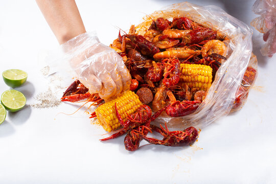 A view of hands opening a plastic bag full of seafood boil, at a local restaurant.