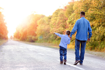 A Happy parent with a child in the park hands on nature travel go along the road