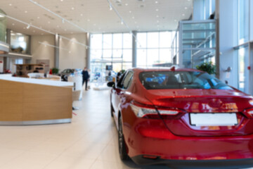 car dealer showroom interior with red car in the foreground, focus on car
