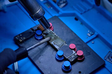 Hands in gloves of professional technician repairman work on chipset pins of removed microprocessor...
