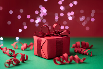 Holiday and Christmas background, gift, serpentine and lights bokeh on red and green background.