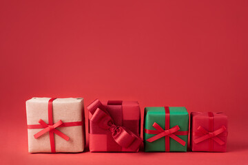 Four Christmas gifts in colorful packaging on a red background.