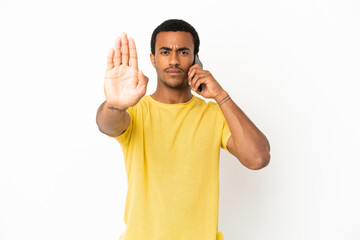 African American handsome man using mobile phone over isolated white background making stop gesture