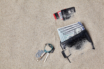 Wallet, dollars, plastic cards and keys left in the sand