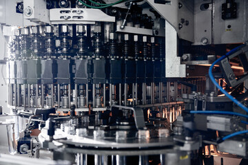 Automatic filling machine pours water into plastic PET bottles at modern beverage plant.