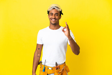 African American electrician man over isolated yellow wall showing ok sign with fingers