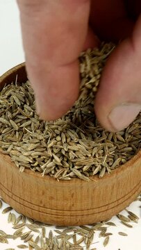 Chef taking chopped dry cumin seeds or zira spices from wooden spice jar. Close-up.