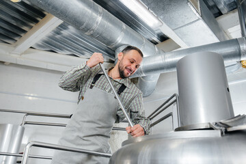 A young male brewer is engaged in the brewing process in a small brewery. Beer production.