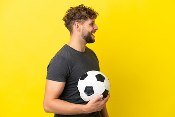 Handsome young football player man isolated on yellow background laughing in lateral position