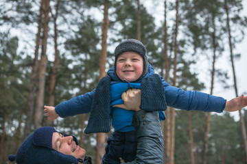 Happy family on a walk outdoors in sunny winter forest, Christmas holidays, father and son play...