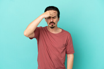 Young caucasian man isolated on blue background with headache